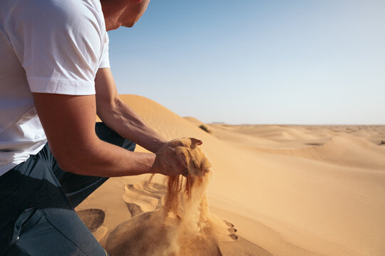 Man picking up desert sand between his hands