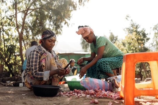 African women cooking in traditional clothing.