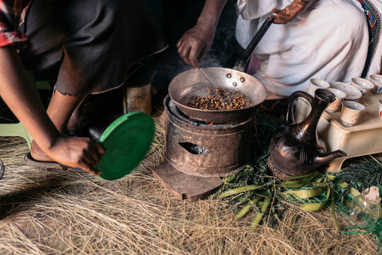 Unrecognizable Ethiopian women roasting coffee at traditional home.