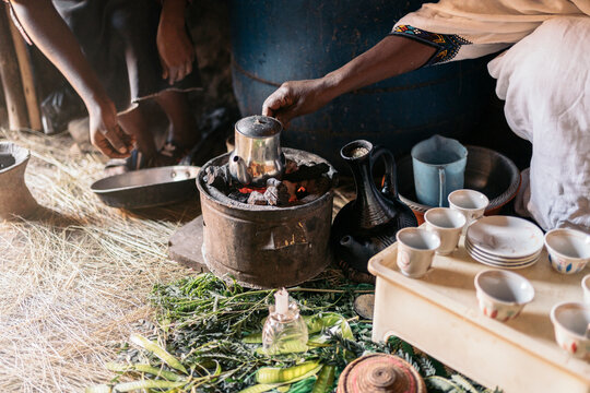 Unrecognizable Ethiopian women roasting coffee at traditional home.