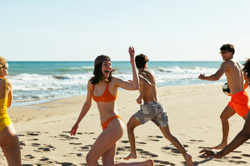 Happy diverse friends walking on beach