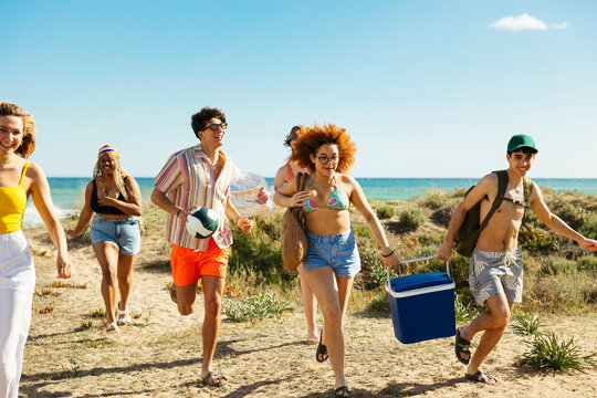 Group of diverse friends running on beach - Powered by Adobe