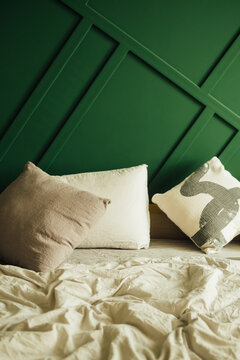 Pillows on Messy Bed with Green Bedroom Wall
