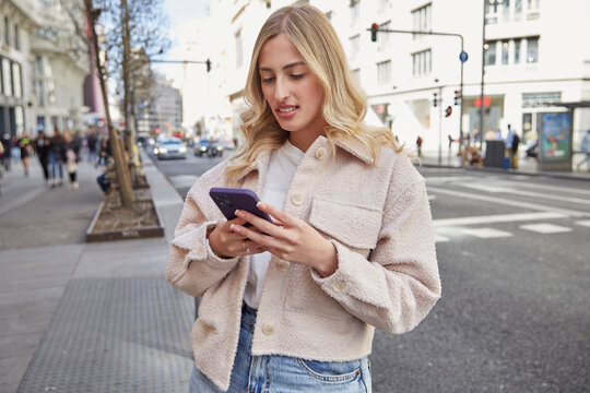 young  woman standing in the city center, texting on her mobile