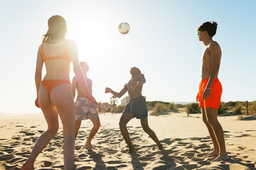 Happy friends playing with ball on beach