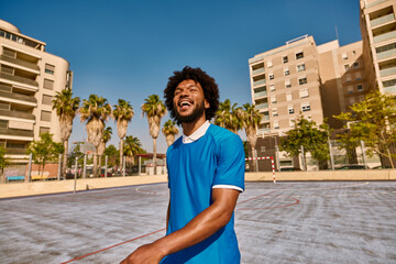 Cheerful black male football player on court