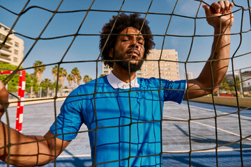 Black football player standing behind net