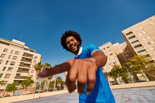 Cheerful black male football player on court