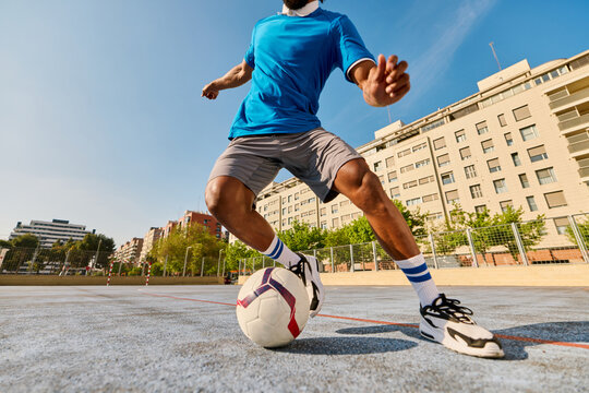 Energetic black football player kicking ball