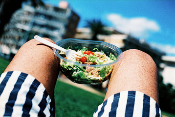 man on the grass about to eat a packaged salad