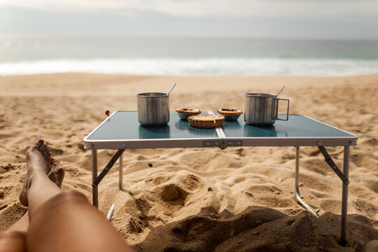 ugc of woman lying on the beach drinking coffee at a beach table