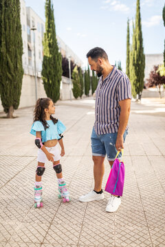 Father helping his daughter to skate in the street