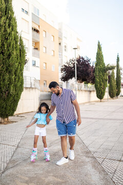 Father helping his daughter to skate in the street