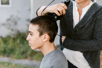 Teenager shaving hair outdoors