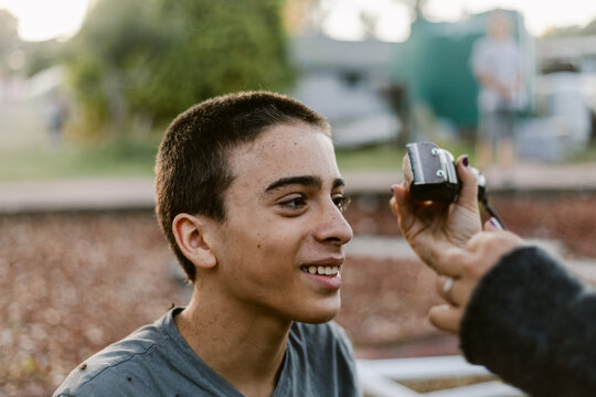 Excited teenager shaving his hair outdoors
