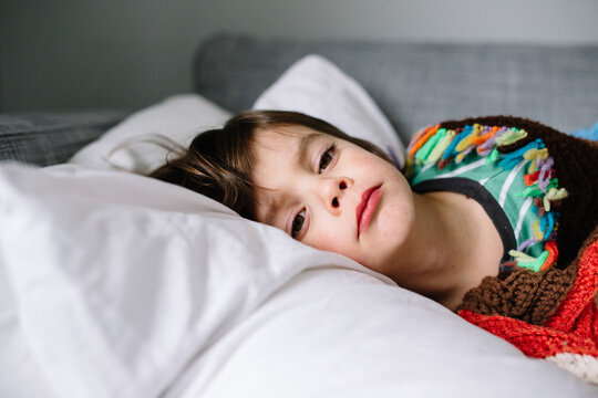 boy lays on couch at home while sick with cold and flu