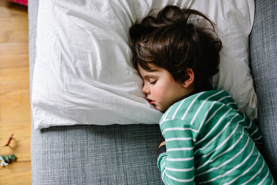Ovehrhead view of boy on couch at home while sick with cold and flu