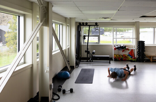 Hard working, fit older man doing burpees in the gym.