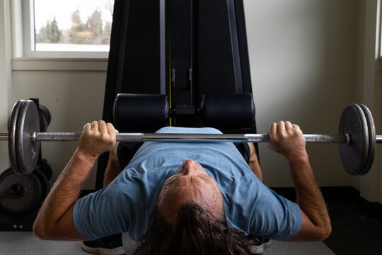 Man doing bench press exercise in rec center gym.