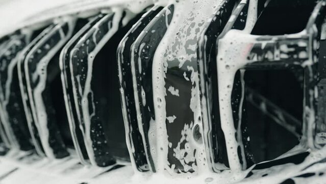 soap and water falls between twin kidney grille of a car forming an interesting little cascade with reflections