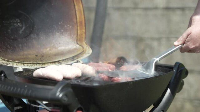 Sausages and burgers cooking on a barbeque in the summer sunshine