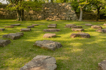 Large flat foundation stones in green lawn of nature park.