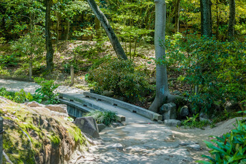 Small wooden footbridge over stream at Shukkeien Gardens in Hiroshima.