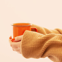 female hands with orange cup of coffee on white background