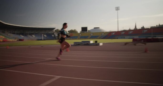 Strong female sprinter running fast during training against sunrise