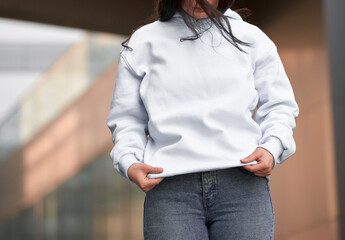 the woman wears a white hoodie. The empty space on her blouse is for logo design and branding...