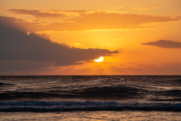 Sunset Behind Clouds with Waves Breaking on Beach in Kauai Hawaii