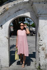 Fototapeta na wymiar Woman walking alone under an old Yogyakarta arch gate in a sunny day