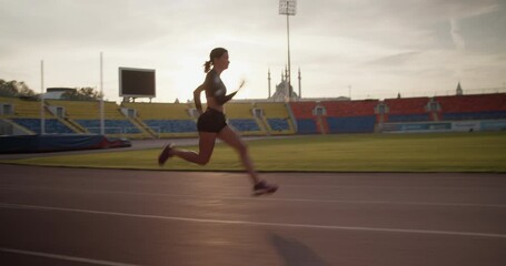 Fit female sprinter running fast in stadium during morning training - Powered by Adobe