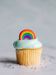 Vanilla cupcakes decorated with pride rainbow on white background.