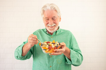 Smiling senior bearded man holding bowl of fresh seasonal fruit ready to eat. Breakfast or lunch, eat healthy and dietary - Powered by Adobe