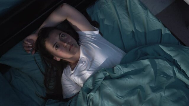 Sleep disorder, insomnia concept. Young woman lying on the bed awake at night