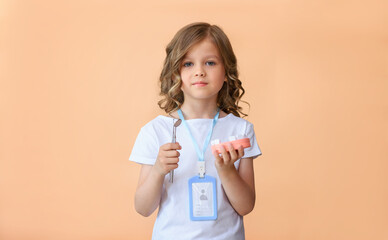 A child is holding a wooden model of a human jaw in close-up  with a dental mirror on a beige background. Dental examination and prevention of dental diseases. National dentists day. 