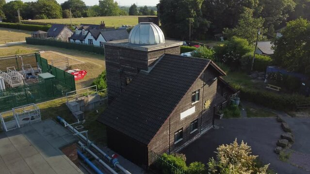Aerial view Pex hill Leighton observatory silver dome rooftop on hilltop farmland at sunrise, low orbit right