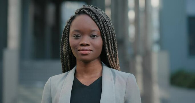 Portrait of Black woman with braided hair standing and looking at camera. 