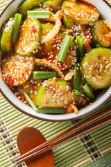Korean food style quick cucumber kimchi or spicy cucumber salad on white bowl Oi Muchim is Korea traditional on the table. Vertical top view from above