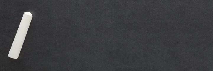 White chalk stick on blackboard background. Closeup. Empty place for text. Top down view.