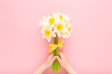 Little baby girl hands holding fresh beautiful flower bouquet of white narcissus with yellow ribbon...