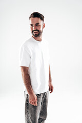 Fototapeta premium Portrait of handsome smiling stylish hipster lambersexual model. Sexy man dressed in white T-shirt and jeans. Fashion male isolated on white background in studio
