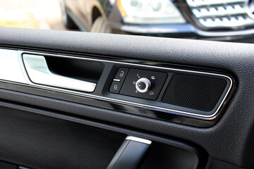 Fototapeta na wymiar Interior of a modern car. Inner driver door handle with lock unlock buttons. Modern Car Door Panel. Speaker in the car door.