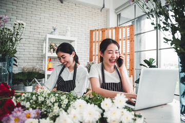Two florists are arranging flowers in a vase to attract customers attention and receive orders from customers via smartphone in the flower shop.