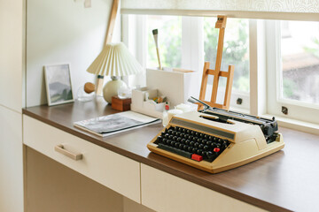 Typewriter isolated on wooden desk. Tiny workspace. Working space. Cozy corner. Simplicity. Home decoration. Apartment. Simple objects. Working room. Vintage design. Oldest typewriter.