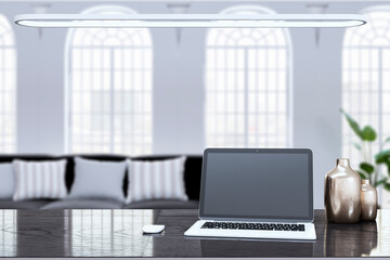 Close up of clean designer office workplace with empty mock up laptop screen and other items. Blurry office interior background. 3D Rendering.