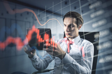 Economy crisis and recession concept with falling down red financial chart candlestick and diagram on trader using digital tablet background, double exposure