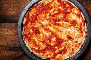 pizza cooking. Dough smeared with tomato sauce.