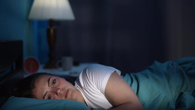 Young woman suffering from insomnia while lying in bed at night